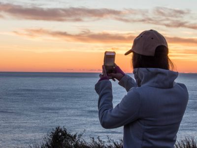 Person taking a sunset photo on her phone from North Head, Sydney Harbour National Park. Photo: Rachel Dimond
