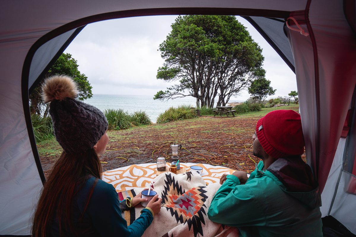 A couple enjoying a hot drink looking out the sea at Trial Bay Gaol campground, Arakoon National Park. Photo credit: Rob Mulally/DPIE