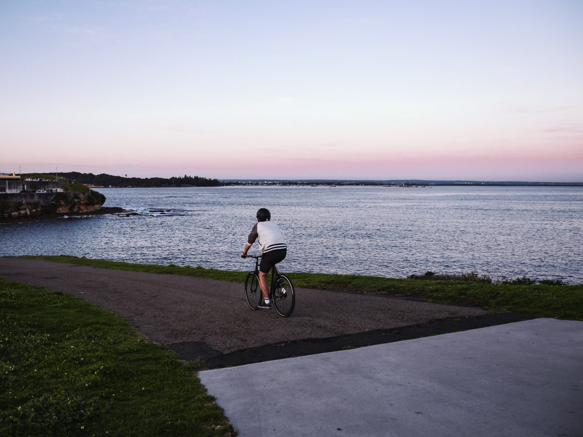 Person riding a bike at sunset along the track to Bare Island, Kamay Botany Bay National Park. Photo: Nick Alfred