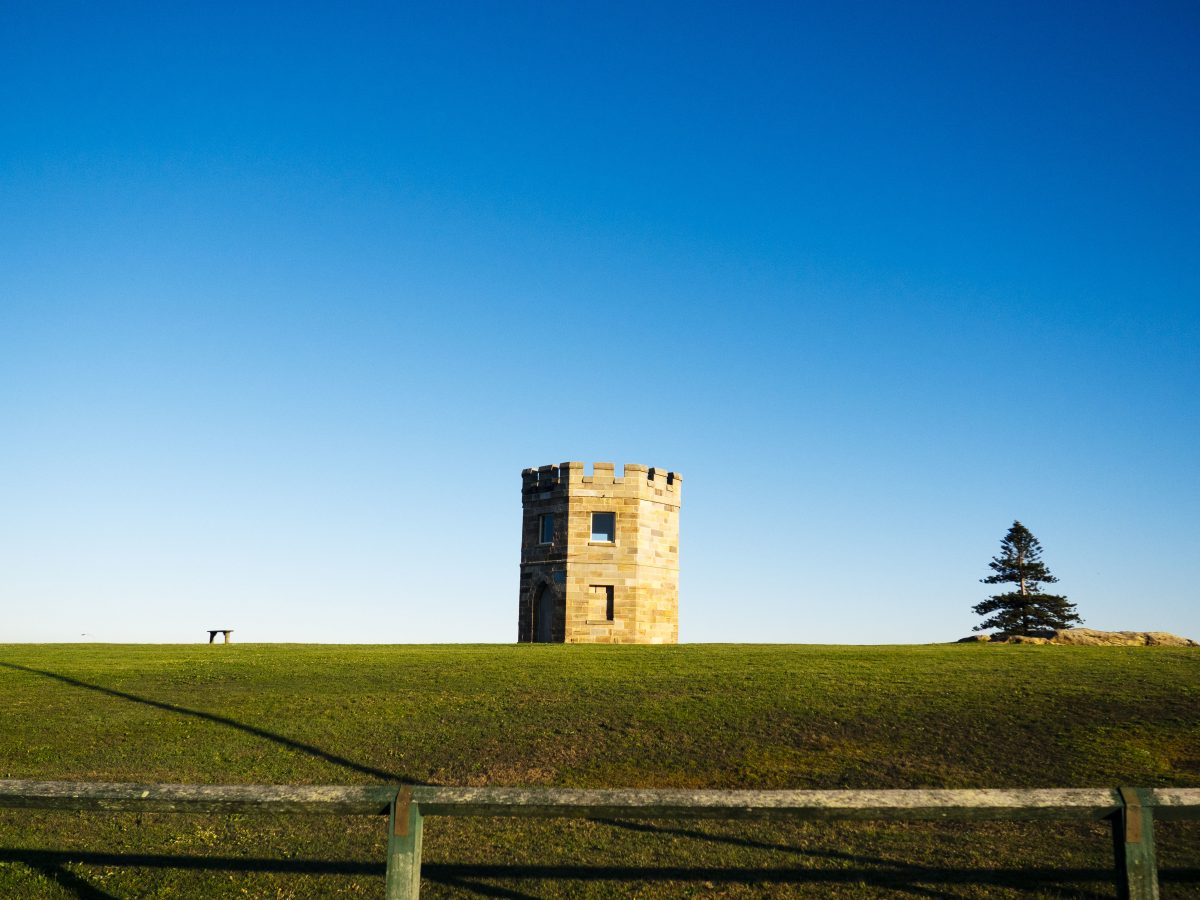 Stone tower peeks over grass hill, Kamay Botany Bay National Park. Photo: Nick Alfred