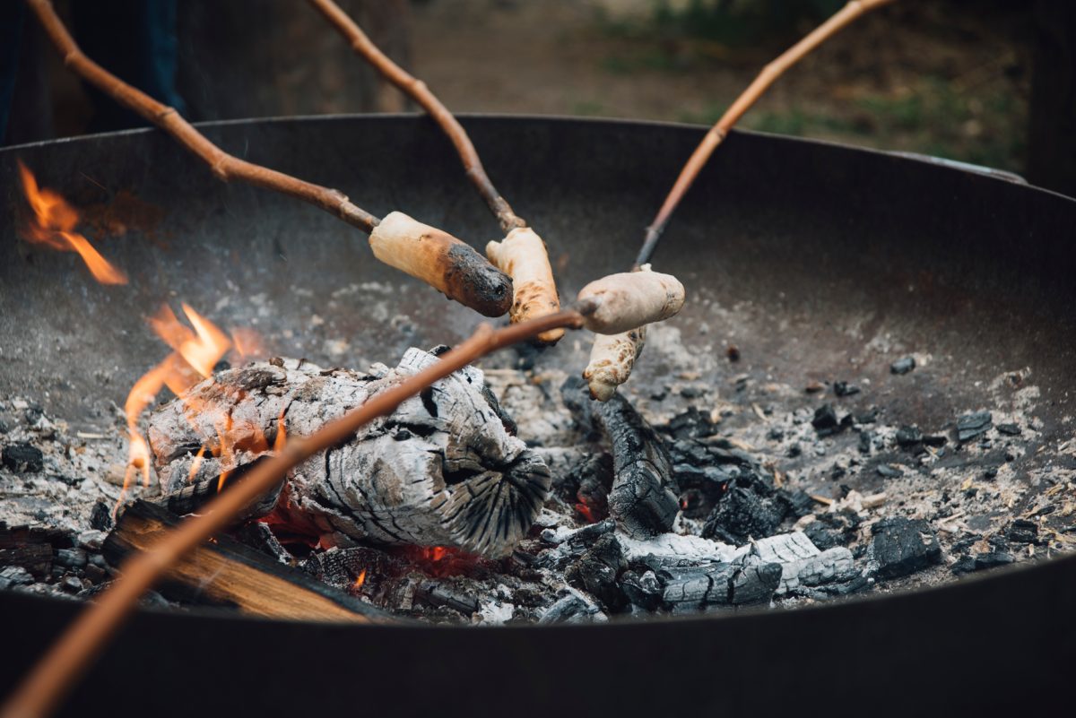 Campfire damper bread baked on sticks over the fire. Photo: Stocksy