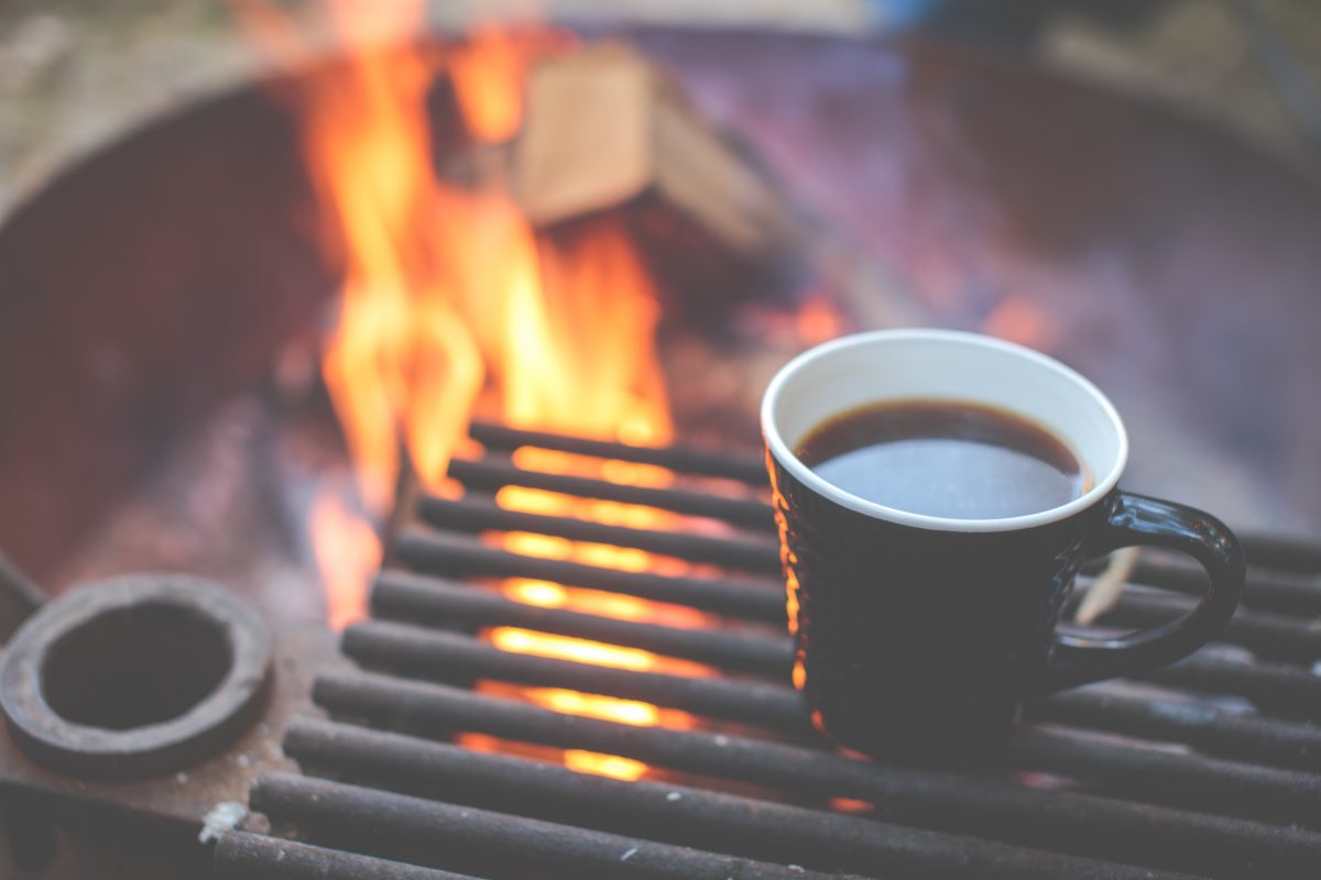 Coffee mug next to a campfire. Photo: Unsplash