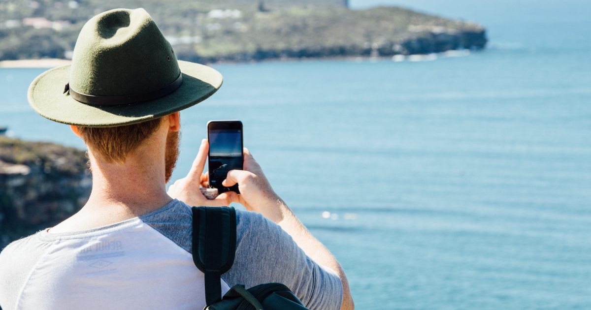 Man taking a coastal photo on his phone. Photo: Jack Bussell