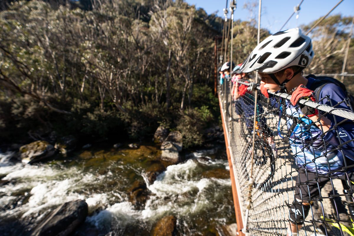 People peering over the bridge to look at the Thredbo Valley river below, Kosciuszko National Park. Photo: Rob Mulally/DPIE