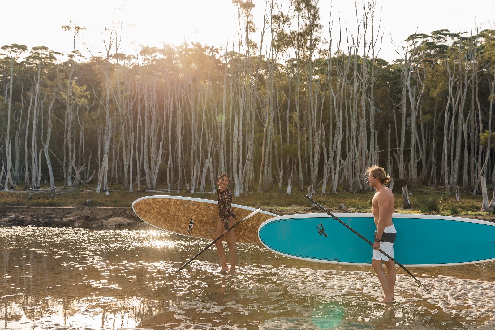 Two people taking their paddleboards to Durras Lake in Murramarang National Park. Photo: Melissa Findley/DPIE