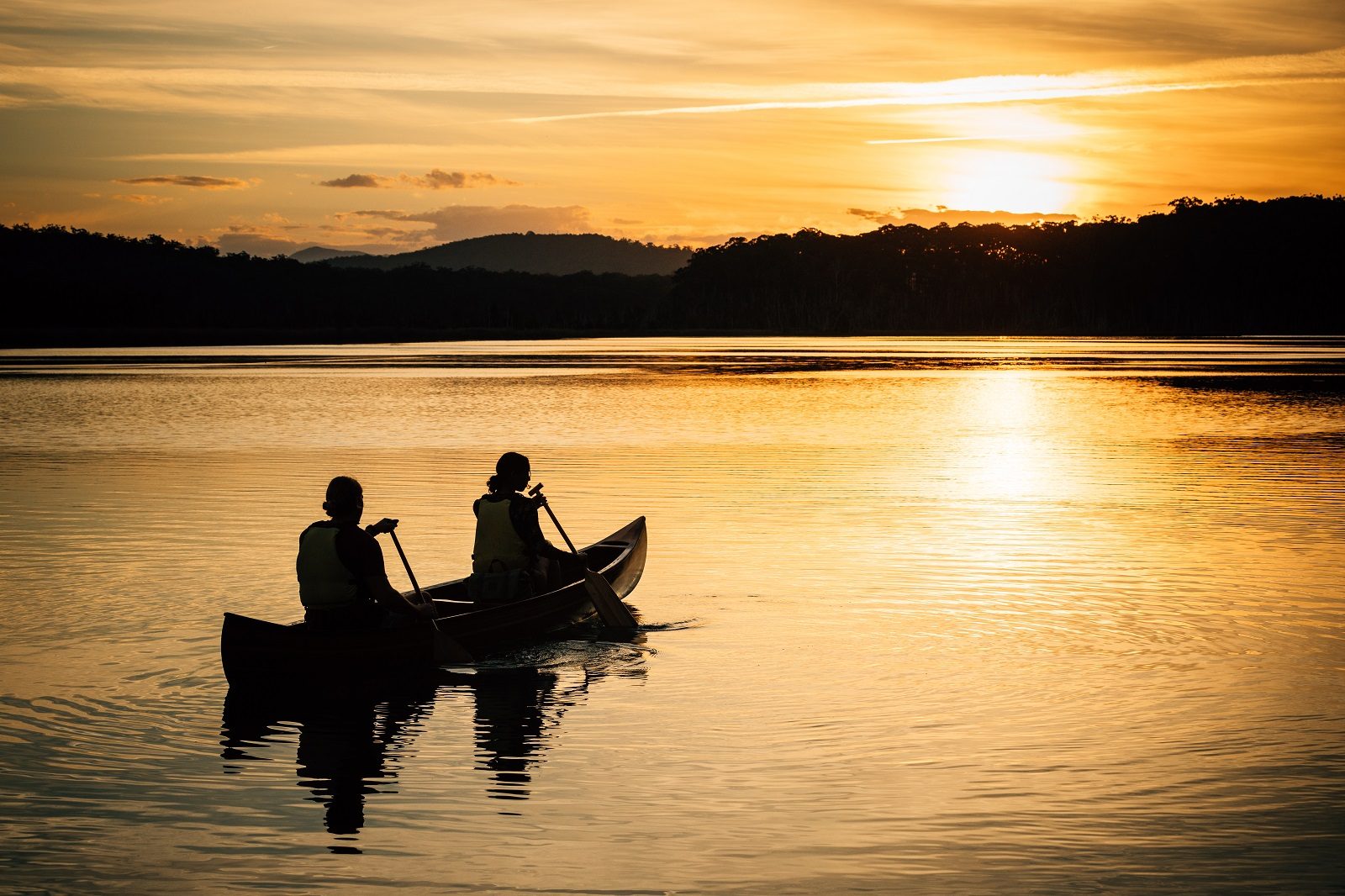 Silhouette of two people canoeing on a lake in Murramarang National Park. Photo: Melissa Findley/DPIE