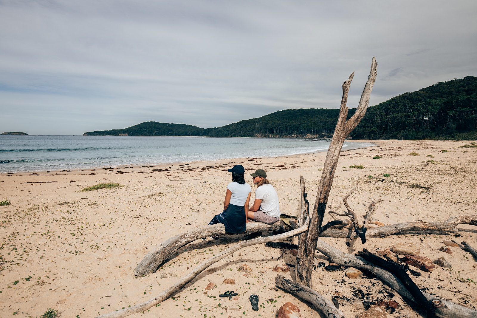 Couple sitting at Pebbly Beach in Murramarang National Park. Photo: Melissa Findley/DPIE