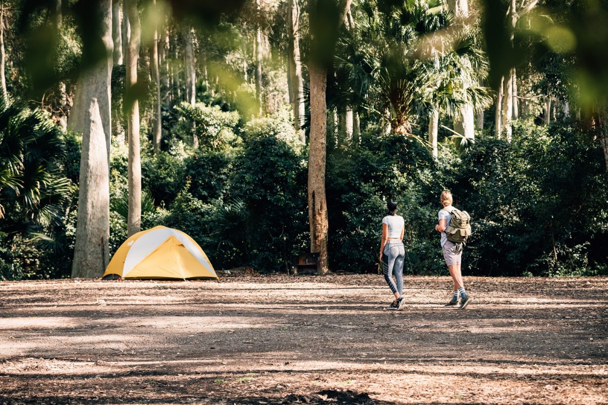 A woman and a man walking to a tent at Depot Beach campground, Murramarang National Park. Photo credit: Melissa Findley/DPIE