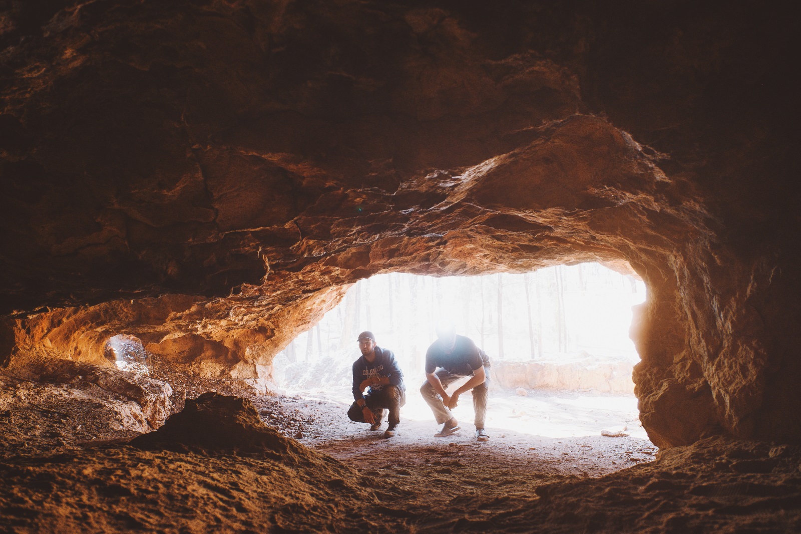 Two men crouching to look in the Salt Caves at the Pilliga in Timmallallie National Park. Photo credit: Harrison Candlin/DPIE