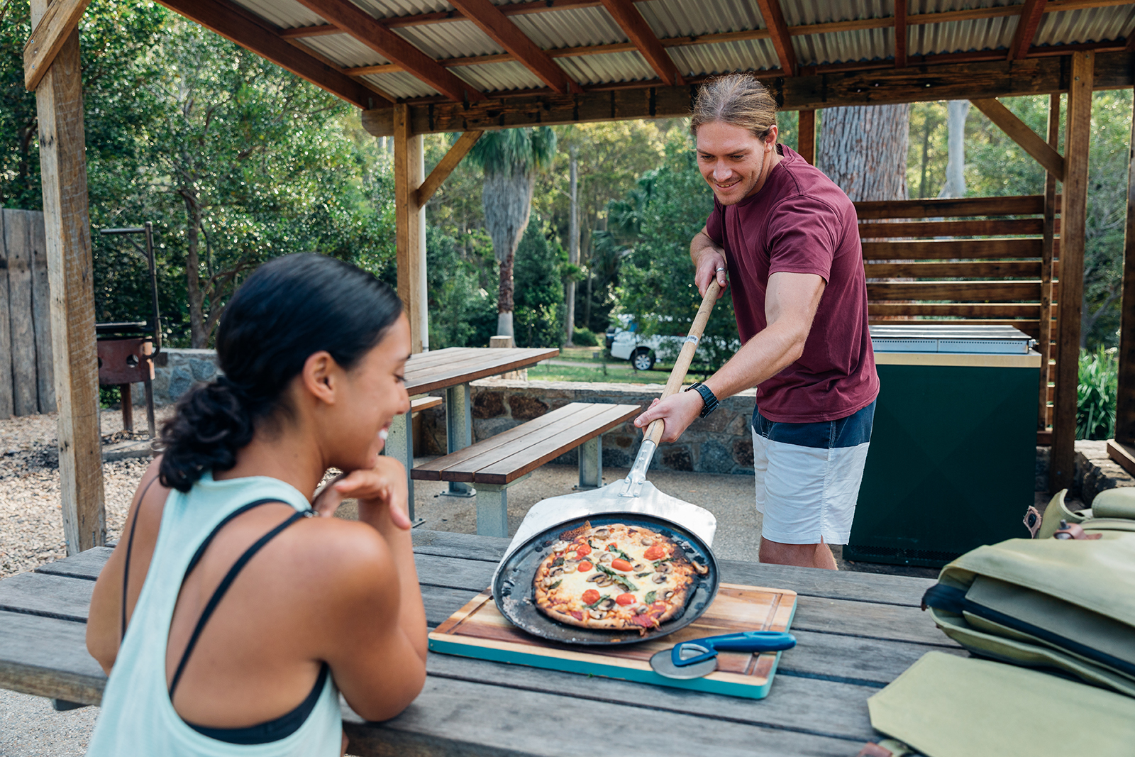 Two people enjoying woodfired pizza in Murramarang National Park. Photo: Melissa Findley/DPIE