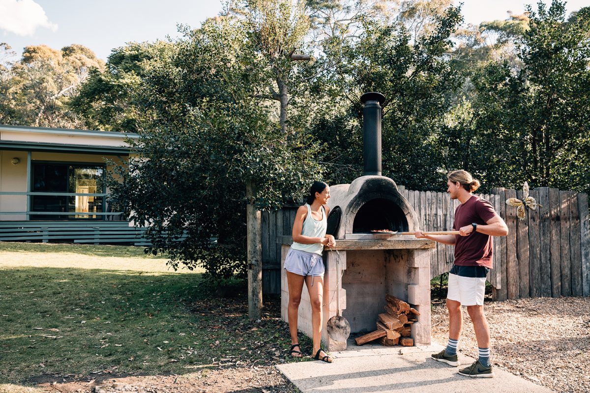 A couple cook a barbecue at Depot Beach cabins, Murramarang National Park. Photo credit: Melissa Findley/DPIE