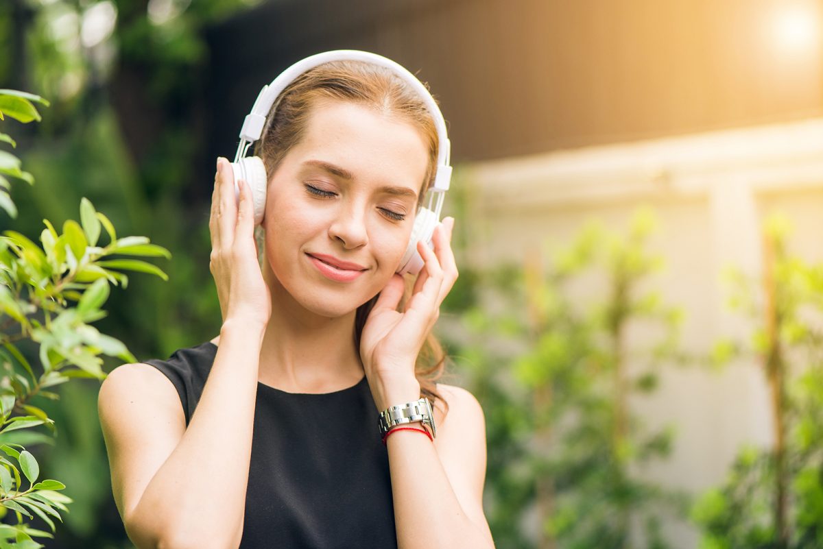 A woman with her eyes closed and earphones on enjoying what she is listening to