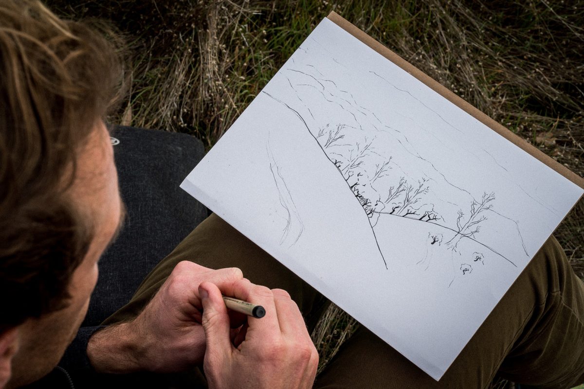 A male with a pen in his hand sketching 