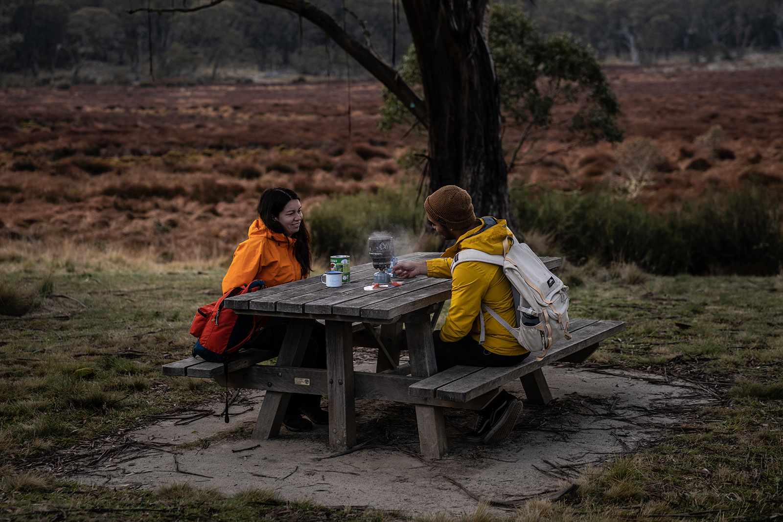 Two people enjoying a hot drink on a picnic bench in Barrington Tops National Park. Photo: Rob Mulally/DPIE