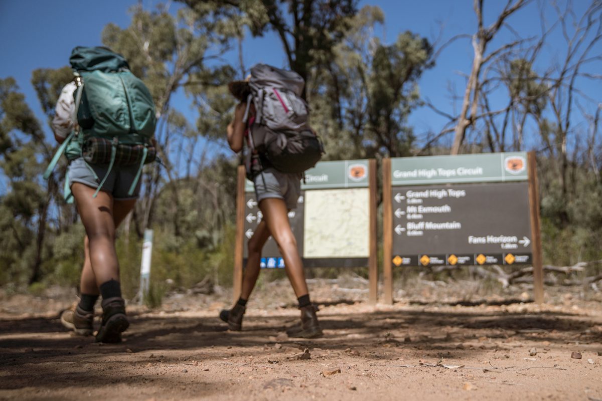 Two people walking past a sign in Warrumbungles National Park