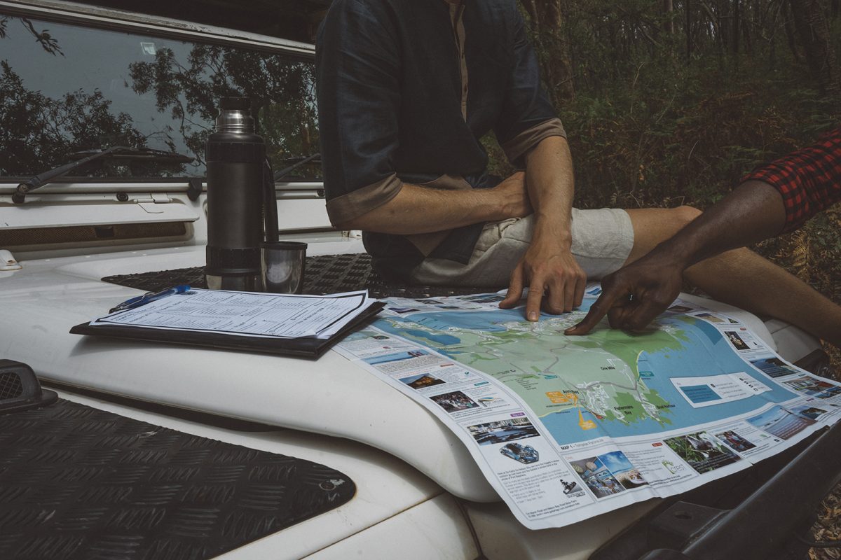 Two people looking at a a map on the hood of their car