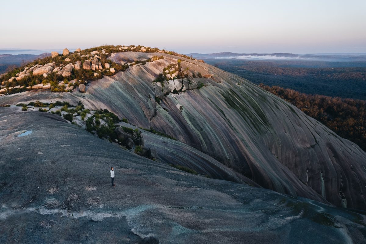 Aerial shot of a person standing on summit of Bald Rock, Bald Rock National Park. Photo: Harrison Candlin © Harrison Candlin / DPE