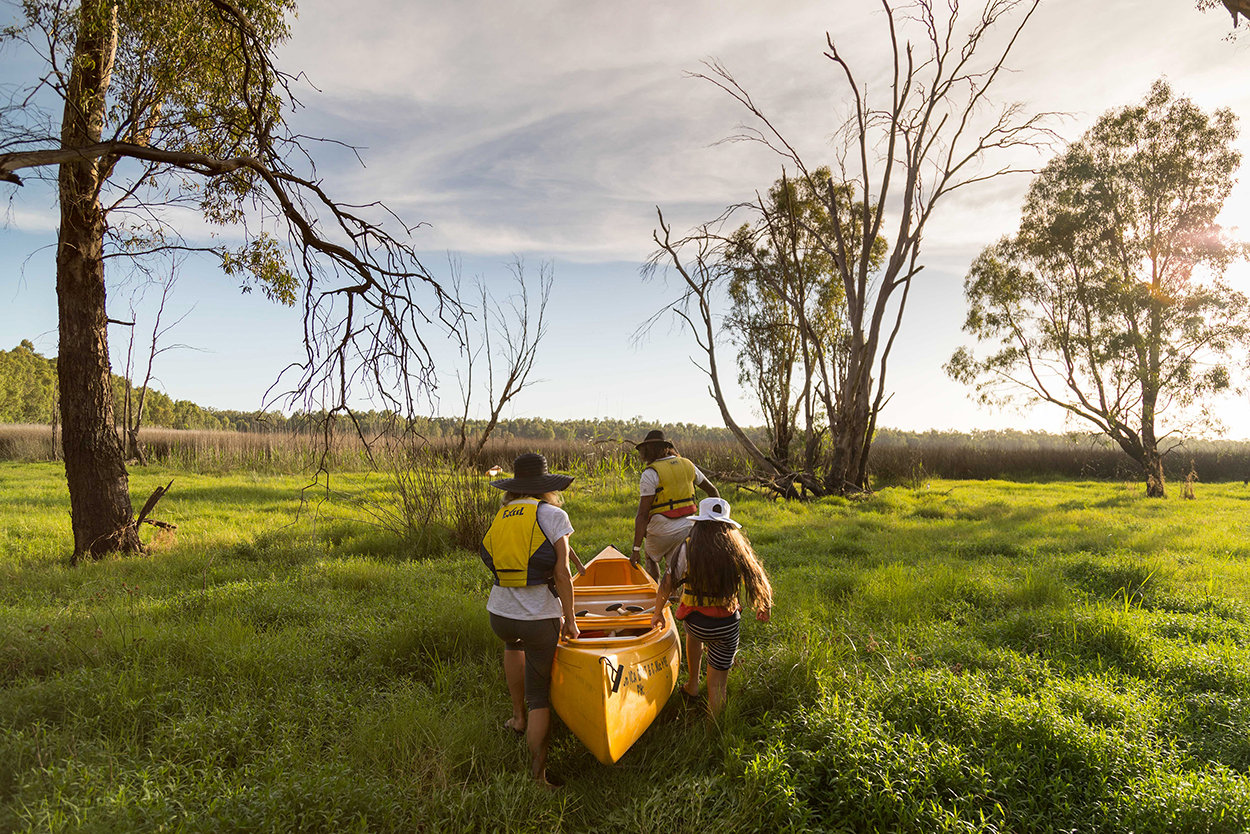 A family of four carrying a canoe in Murray River National Park. Photo credit: Boen Ferguson / DPE