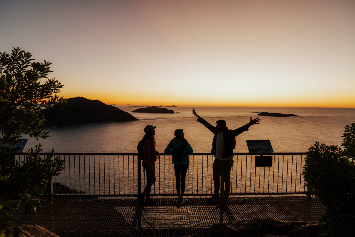 Three people at Tomaree Head Summit at sunrise. Tomaree Coastal Walk, Tomaree National Park. Photo credit: Remy Brand / DPE