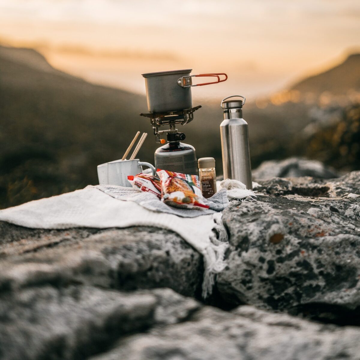 A tumbler next to a cooking pot on a portable stove Photo credit: Taryn Elliott via Pexels