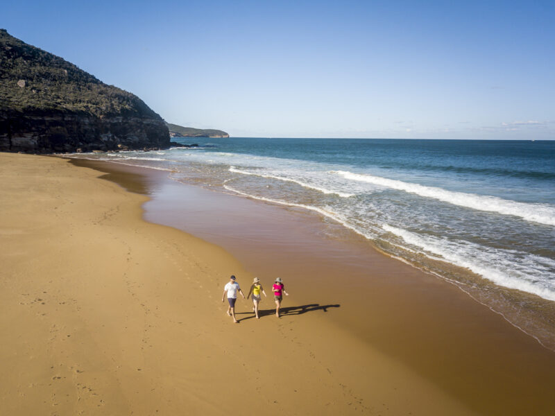 Aerial of three people walking along Tallow Beach, Bouddi National Park. Photo: John Spencer / DPE