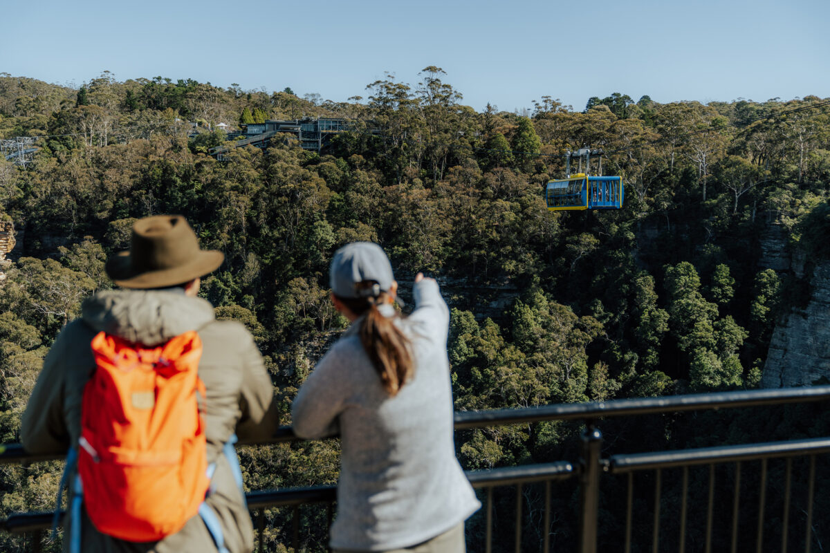 Two people at Cliff View lookout, and Scenic world cable car. Blue Mountains National Park. Photo credit: Remy Brand / DPE
