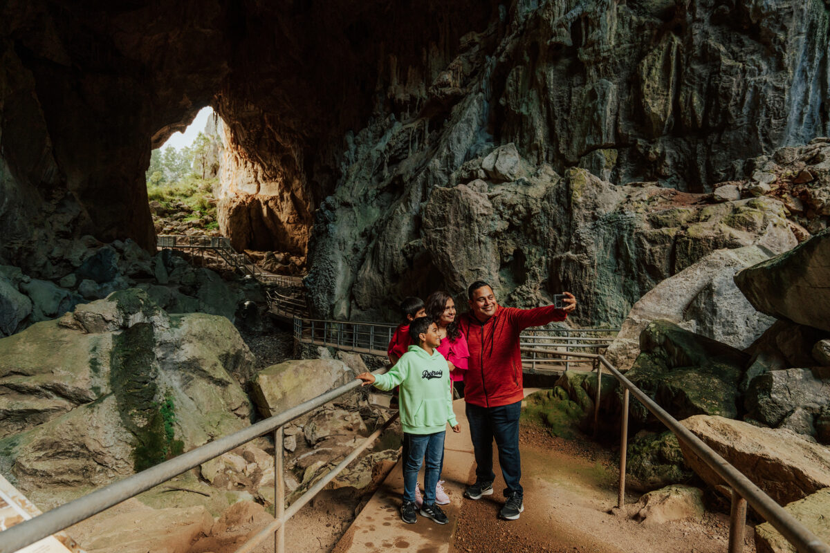 A family of four taking a selfie in Victoria Arch, Womebyan Caves, Wombeyan Karst Conservation Area. Photo credit: Remy Brand / DCCEEW