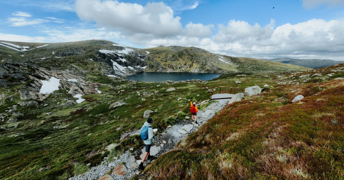 Two walkers take in the veiw from Blue Lake lookout on the Snowies Alpine Walk. Photo credit: Daniel Parsons/DCCEEW