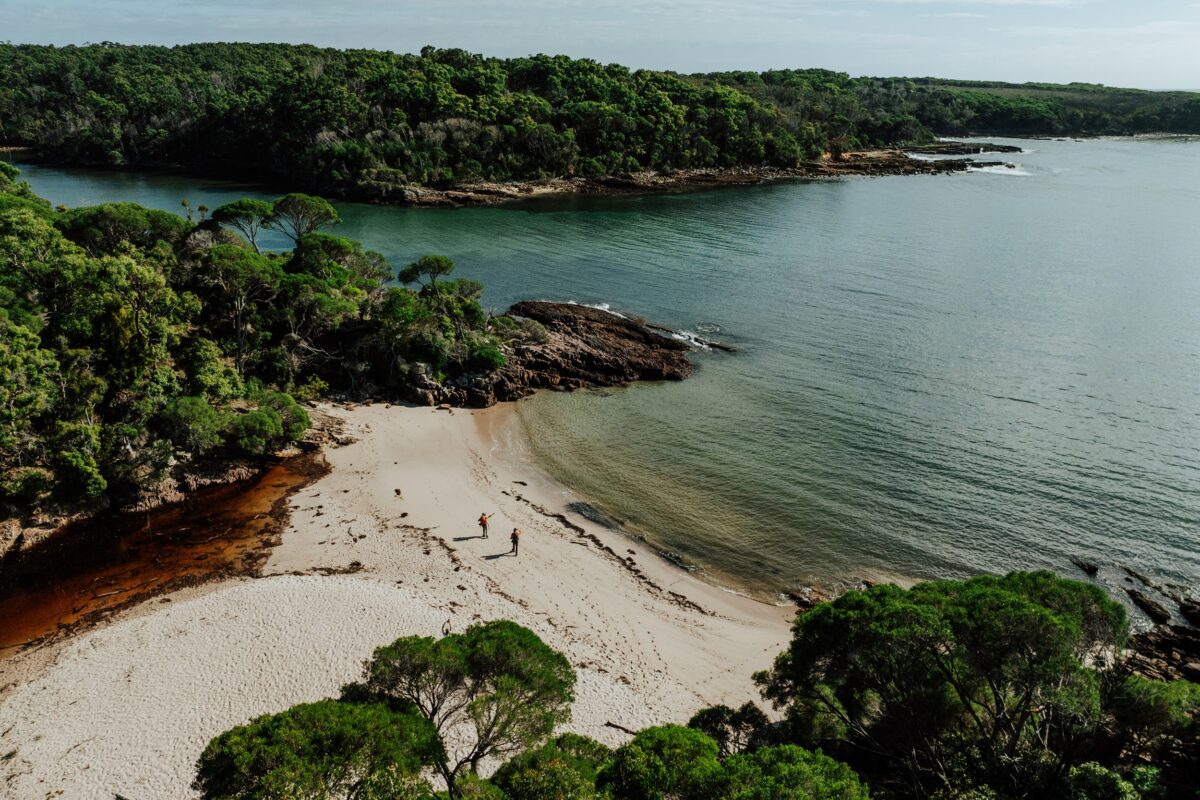 Two walkers at Bittangabee Bay on the Light to Light Walk. Photo credit: Daniel Parsons/DCCEEW