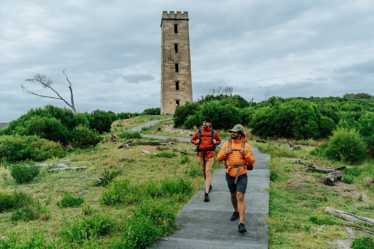 Two walkers at Boyds Tower on the Light to Light Walk. Photo credit: Remy Brand/DCCEEW