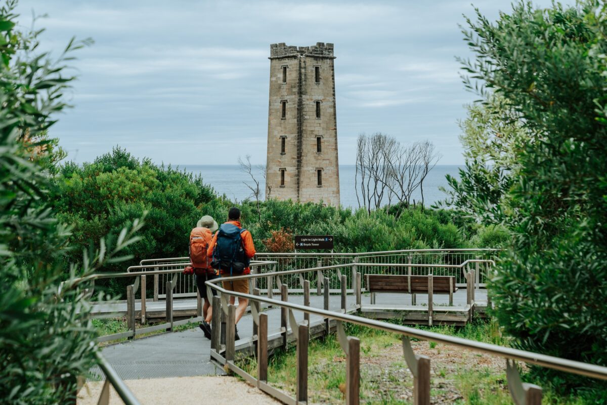 Two walkers at Boyds Tower on the Light to Light Walk. Photo credit: Remy Brand/DCCEEW