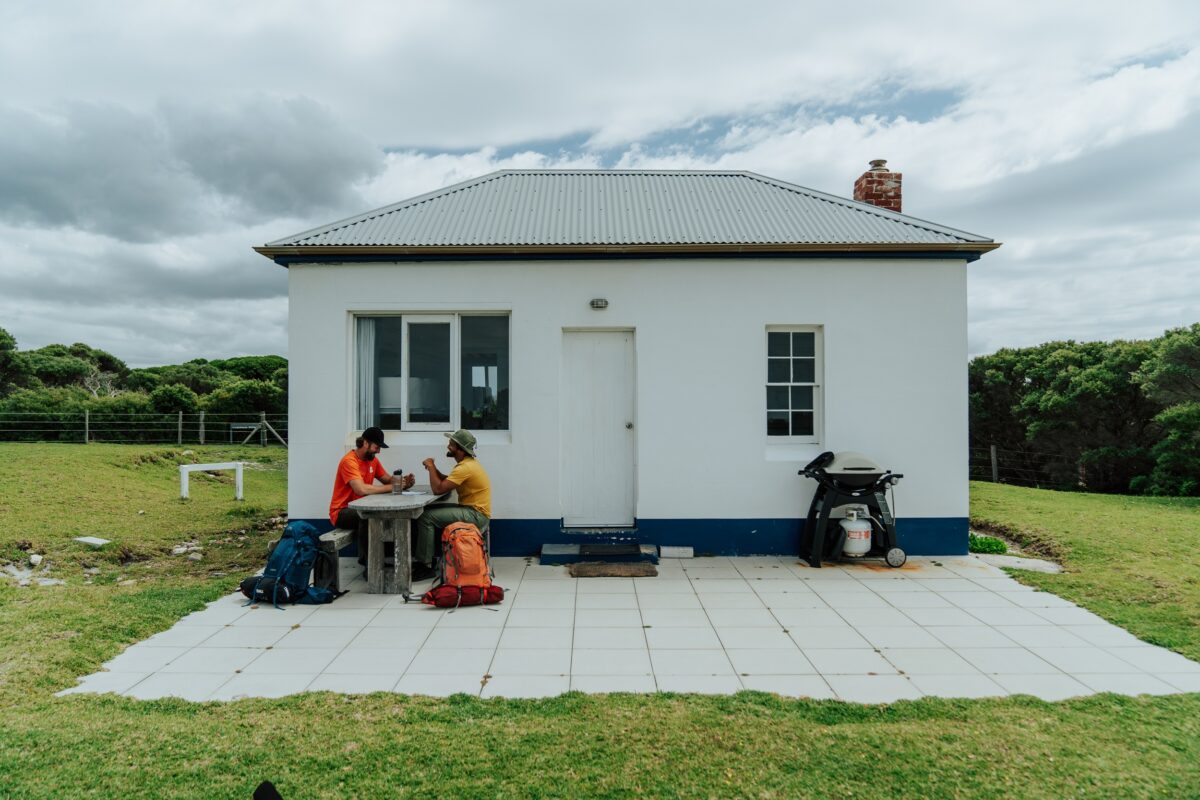 Two walkers take a break at Green Cape Lighthouse on the Light to Light Walk. Photo credit: Remy Brand/DCCEEW