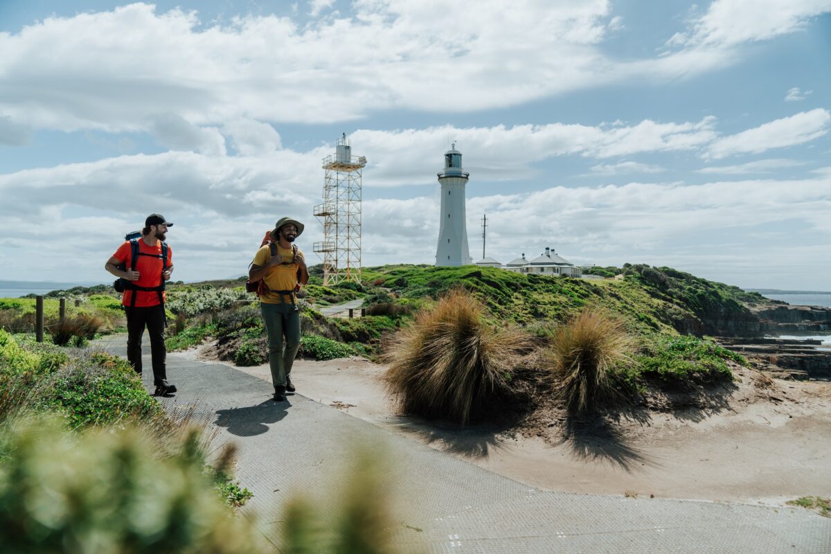 Two walkers at Green Cape Lighthouse on the Light to Light Walk. Photo credit: Remy Brand/DCCEEW
