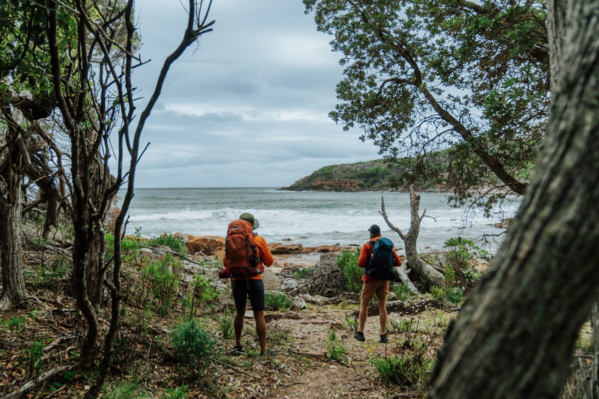 Two walkers at Leather Jacket Bay on the Light to Light Walk. Photo credit: Remy Brand/DCCEEW