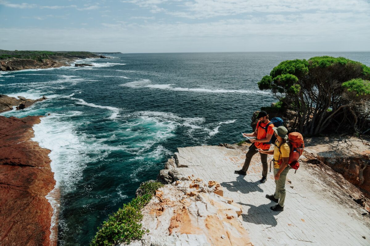 Two walkers take in veiws of the coastline from Pulpit Rock on the Light to Light Walk. Photo credit: Remy Brand/DCCEEW