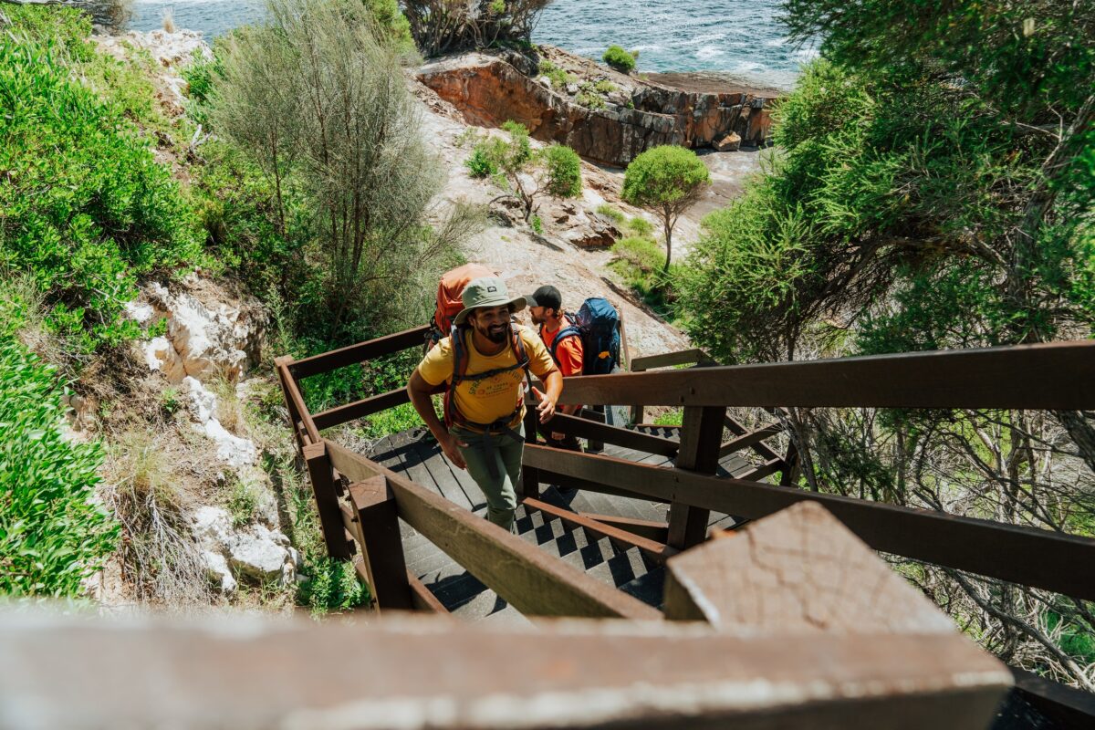 Two walkers climb the stairs at Pulpit Rock on the Light to Light Walk. Photo credit: Remy Brand/DCCEEW