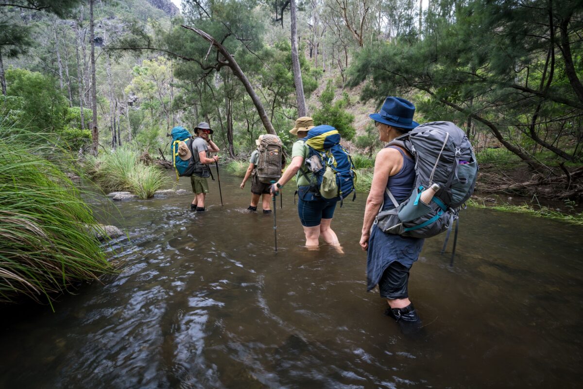A group of hikers crossing a river on Green Gully Track.