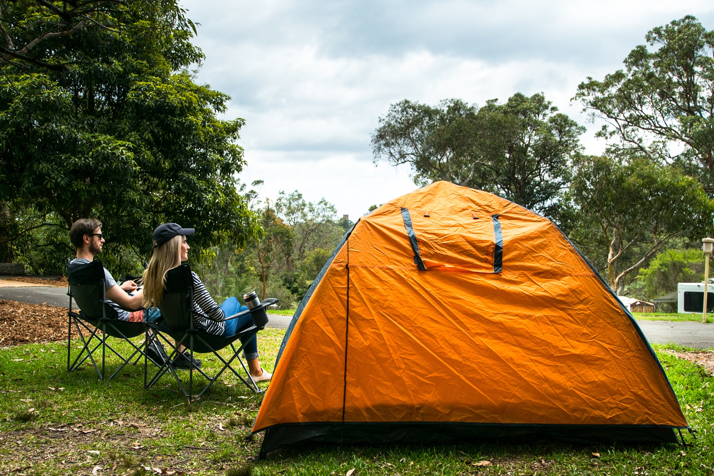 A couple relaxing beside their tent in Lane Cove Caravan Park.
