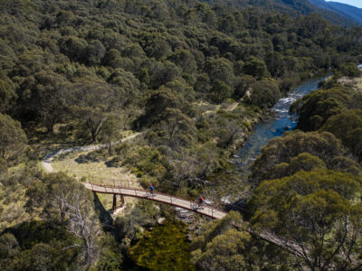 Two people cycling over a briddge on the Thredbo Valley Track in Kosciuszko National Park. Photo Credit: Rob Mulally / DCCEEW